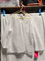 Full front view of white crochet top on hanger