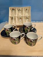 Four espresso cups with saucers and boxed set of six shot glasses on tabletop