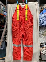 Full view of front of orange high-vis bib overalls hanging