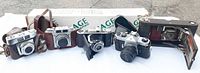 Group shot of five vintage cameras and boxed tripod