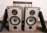 Amplifier on top of both Paradigm 5SE speakers with grills leaning against cabinets