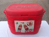 Front view of red Coca-Cola cooler with embossed logo and promotional sticker