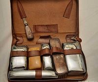 Open toiletry case showing all chrome containers, plastic items, shoehorn and interior layout