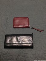 Top view showing both wallets: red Rebecca Minkoff compact and black Mancini long style