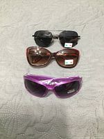 Three pairs of sunglasses stacked showing front view and colours