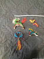 Top view of all four silk ornaments on quilted surface with ruler for scale