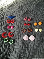Group of ten pairs plastic earrings plus additional plastic earrings on right column