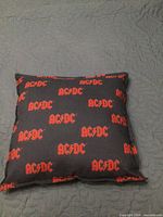Front view of black square pillow with repeating AC/DC logos
