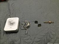 Group shot showing pocket watch, tie clip, cufflinks, and tin box