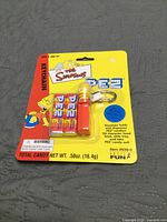 Front of sealed Simpsons Pez keychain package showing dispenser and candy refills