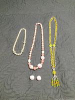 Three necklaces and matching earrings arranged on dark surface