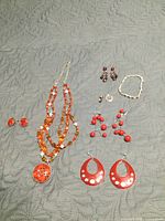 Entire lot laid out showing necklace, five pairs of earrings, bracelet and charms