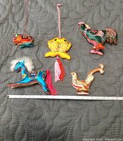 All five embroidered silk animal ornaments arranged together beside a ruler for scale