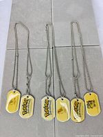 Six dog tag necklaces laid out showing both sides of tags