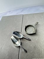 Two small metal scoops and one mini pan on surface