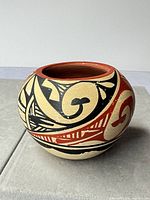 Front view showing geometric black and red design on beige clay pot