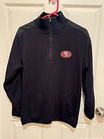 Front view of black quarter-zip pullover showing 49ers logo