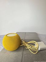 Yellow Apple HomePod mini with braided cable and white power adapter