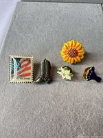 Group shot of five enamel lapel pins on grey background
