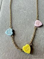 Full necklace laid flat with three enamel heart charms visible