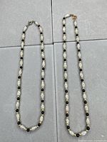 Both necklaces laid flat showing overall design and length