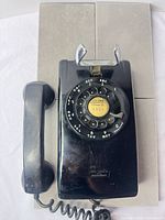 Full view of black wall-mount Western Electric rotary phone with handset and cord