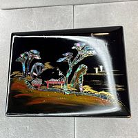 Top view of black lacquer box showing gold painted landscape and mother-of-pearl inlay