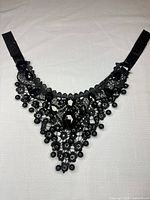 Full view of black lace bib necklace showing overall shape and ribbon ties