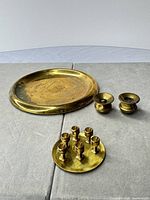 Overview of brass tray, plate with posts, and two candle cups