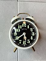 Front view showing entire Bulova alarm clock, dial details, feet and case color