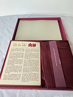 Open burgundy box showing booklet and folded napkins
