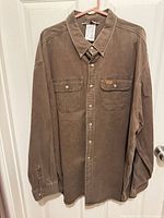 Front view of brown Carhartt button-up work shirt hanging, shows overall design and condition