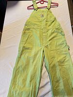 Full view of Carhartt light green bib overalls laid flat