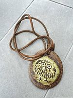 Front view of green glazed owl pendant on leather cord