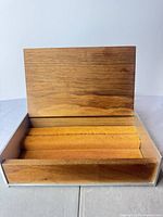 Open jewelry box showing wood lid, orange velvet ring rolls, metal frame