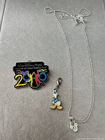 Full lot showing pin, Donald charm and Mickey necklace