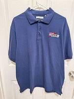 Full view of navy FeatherLite polo on hanger