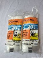 Two sealed Frost King plastic drop cloth rolls side by side