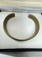 Top view of gold-tone open cuff bracelet showing overall shape