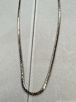Full view of gold-tone herringbone necklace laid flat