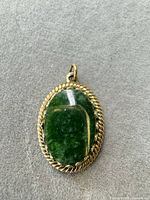 Front view showing green glass stone and gold-tone rope bezel