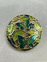 front view of circular green/teal enamel butterfly brooch