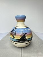 Front view of ceramic vase showing painted landscape and color bands