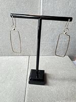 Full pair of rectangular wire dangle earrings on stand