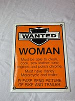Full view of orange metal sign with "Wanted Woman" text