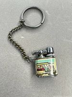 overall view of lighter with key ring and chain attached showing enamel tram scene