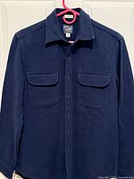 Front view of navy J.Crew shirt jacket hanging, full garment visible