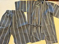 Full view of jinbei jacket and pants laid flat showing stripe pattern and overall condition