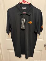Front view of black Kappa polo shirt hanging, tags attached