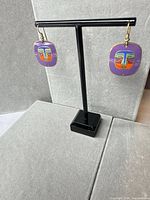 Both earrings on stand showing overall shape and colors